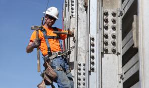 How we work Two construction workers in hard hats smiling.