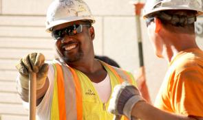 Two construction workers in hard hats smiling.